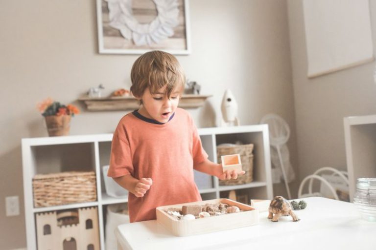 Child Learning - boy in orange crew neck t-shirt standing in front of white wooden table with cupcakes