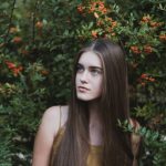 Teenage Behavior - woman standing next to red flower