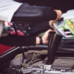 Car Maintenance - man refilling motor oil on car engine bay