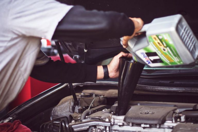 Car Maintenance - man refilling motor oil on car engine bay
