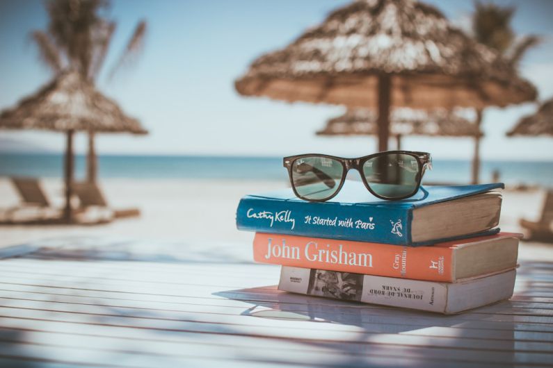 Vacation Planning - black framed Ray-Ban Wayfarer sunglasses on top of book