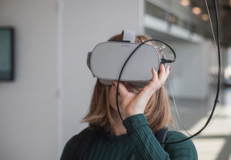 VR Technology - woman in black sweater holding white and black vr goggles