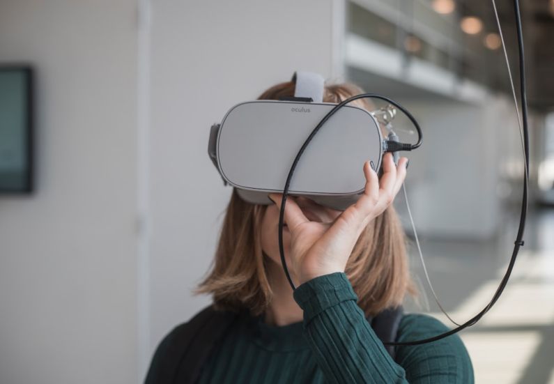 VR Technology - woman in black sweater holding white and black vr goggles