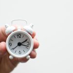 First-time Investing - person holding white mini bell alarmclock