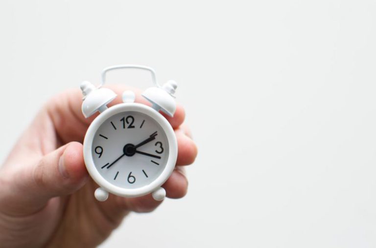 First-time Investing - person holding white mini bell alarmclock