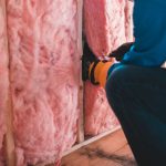 Home Insulation - person in blue pants sitting on brown wooden floor