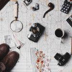 New Zealand Adventure - camera, pair of brown shoes, white ceramic mug, grey and black pen, brown smoking pipe