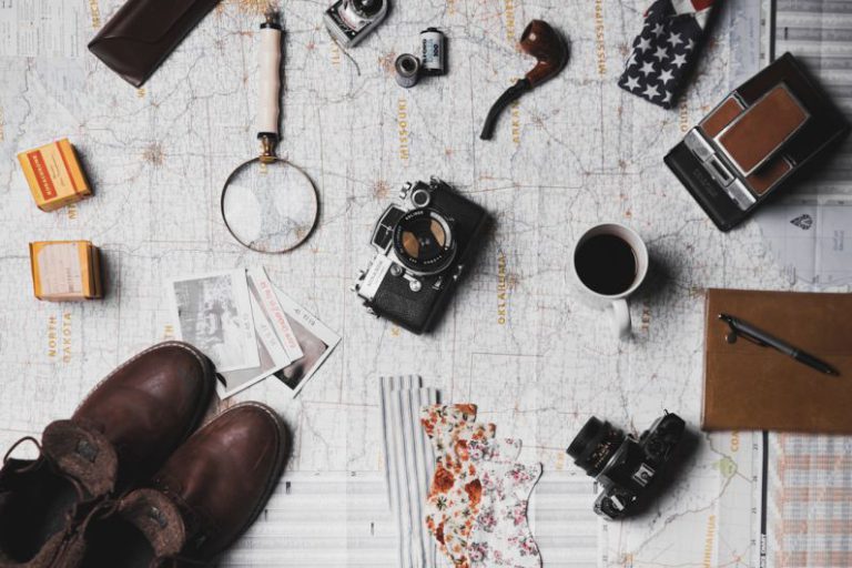 New Zealand Adventure - camera, pair of brown shoes, white ceramic mug, grey and black pen, brown smoking pipe