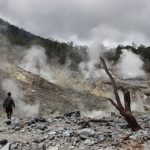 Eco-friendly Travel - a man standing in a rocky area with steam coming out of the ground