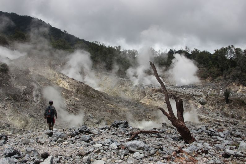 Eco-friendly Travel - a man standing in a rocky area with steam coming out of the ground