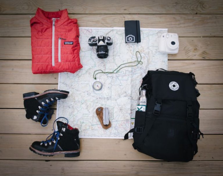 Camping Guide - black hiking backpack near white Fujifilm instax mini camera near black leather boots, red half-zip jacket, gray pocket watch on white map
